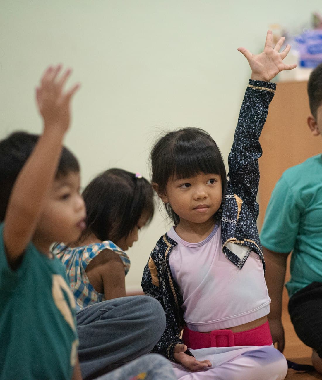 Anak-anak antusias mengangkat tangan di kelas