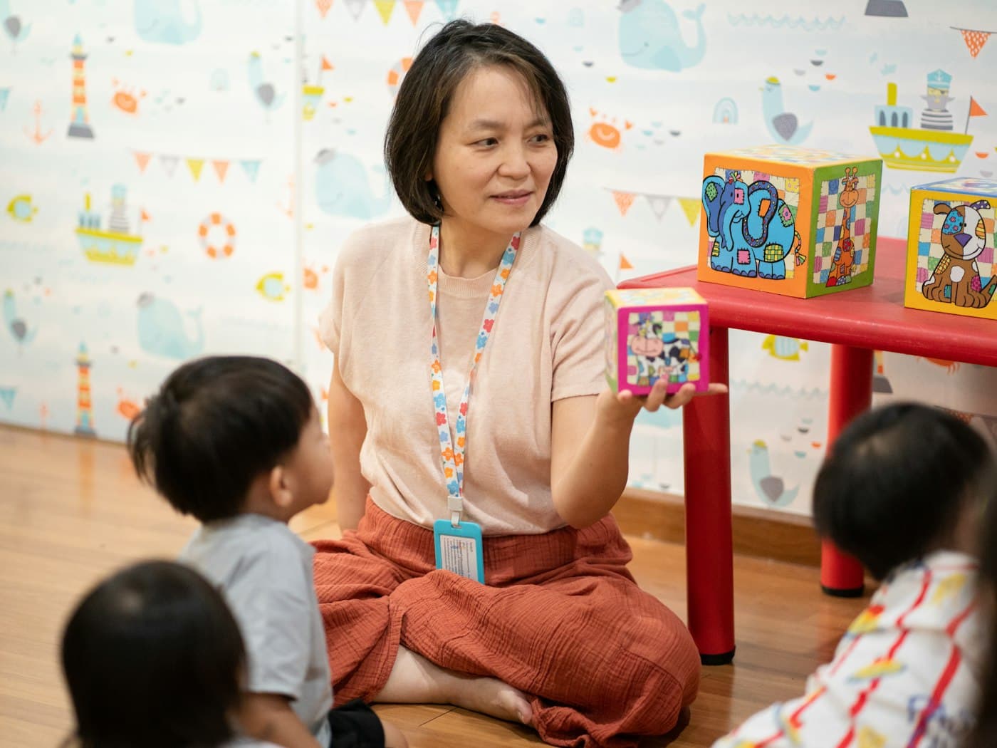 Guru menunjukkan balok warna-warni kepada anak-anak